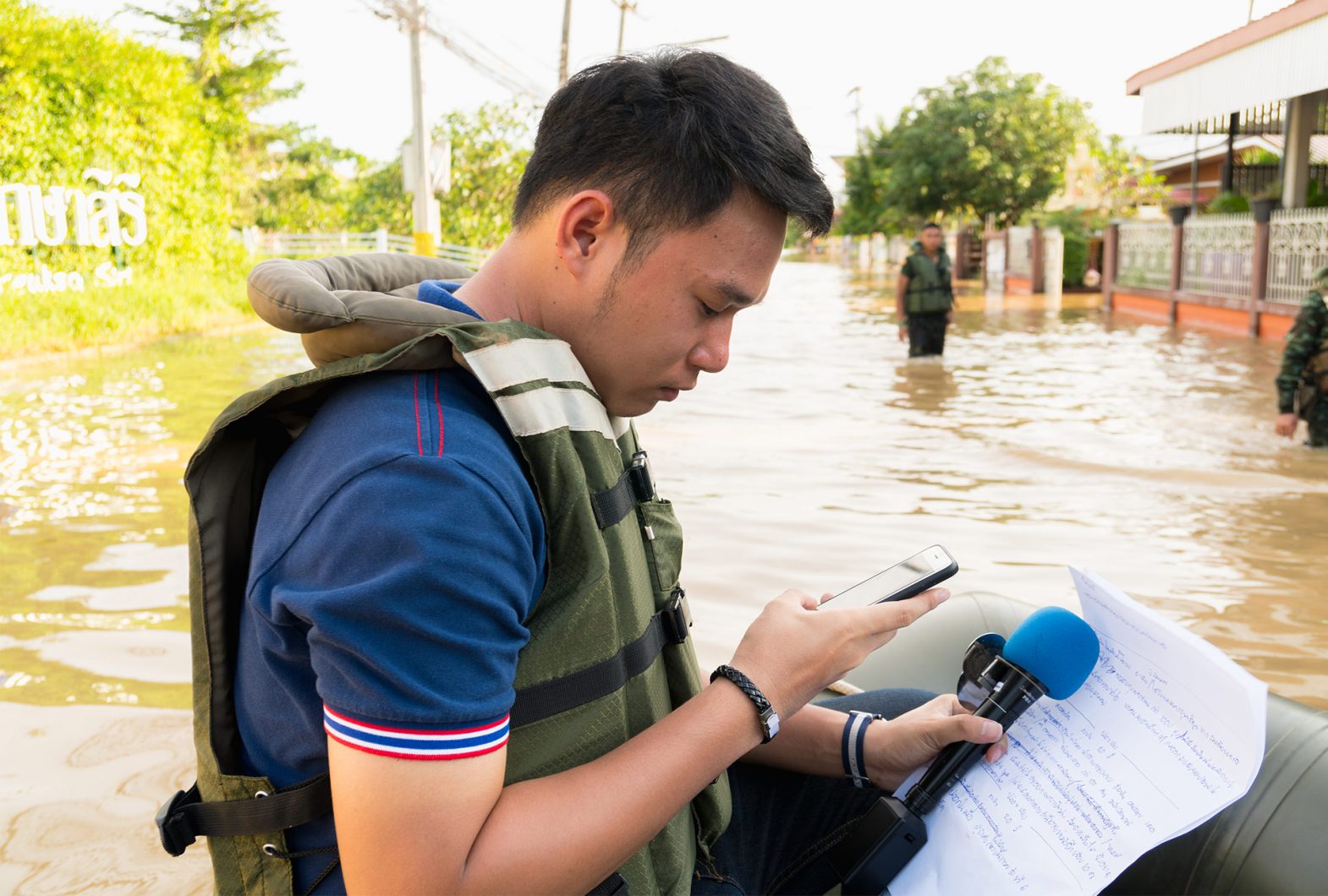 Person looking at phone while wading in a flood.